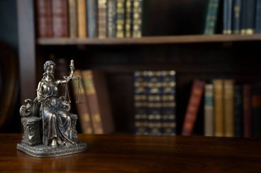 Hukuk ve adalet kavramı. Yargıç odası. Kahverengi masadaki heykel. Kitaplıkta yasal kitap koleksiyonu.