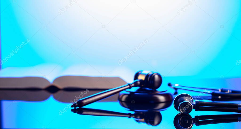 Medical law concept. Gavel, legal code and stethoscope on the glass table. Blue light.