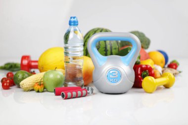 Fitness konsepti. Sağlıklı beslenme: meyve ve sebze. Spor aletleri: tartı makinesi ve dambıllar. Beyaz arkaplan.