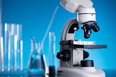 Bilim konsepti. Laboratuvar ekipmanı bileşimi. Mavi arkaplanda test tüpleri ve mikroskop.