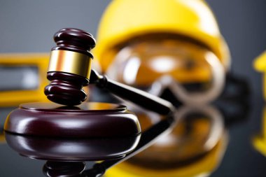 İnşaat hukuku kavramı. Gri arkaplanda miğfer ve hakimler tokmak.