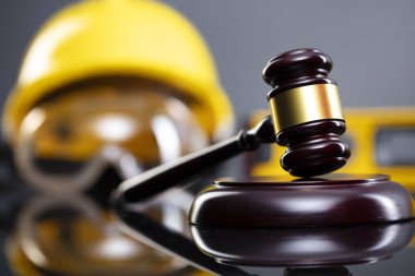 İnşaat hukuku kavramı. Gri arkaplanda miğfer ve hakimler tokmak.