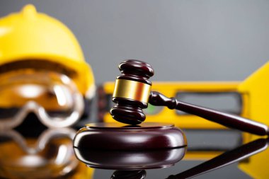 İnşaat hukuku kavramı. Gri arkaplanda miğfer ve hakimler tokmak.
