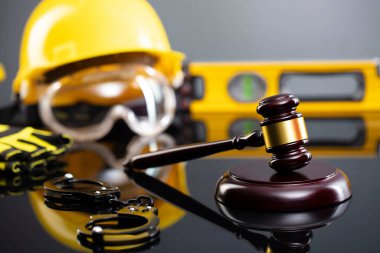 İnşaat hukuku kavramı. Gri arkaplanda miğfer ve hakimler tokmak.