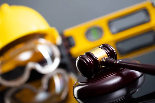 Construction law concept. Helmet and judges gavel on the gray background.