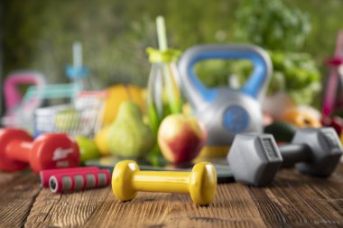 Fitness konsepti. Sağlıklı beslenme: meyve ve sebze. Spor aletleri: ağırlık ölçme makinesi ve dambıl. 