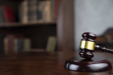 Hukuk teması. Yargıç odası. Yargıç tokmağı kahverengi masaya. Kitaplıkta yasal kitap koleksiyonu.