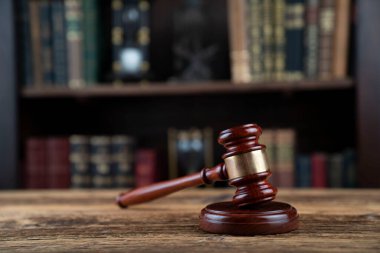 Hukuk teması. Yargıç odası. Yargıç tokmağı kahverengi masaya. Kitaplıkta yasal kitap koleksiyonu.