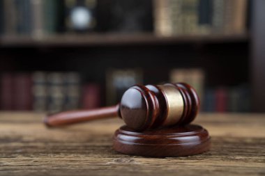 Hukuk teması. Yargıç odası. Yargıç tokmağı kahverengi masaya. Kitaplıkta yasal kitap koleksiyonu.