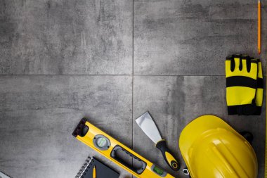Müteahhit konsepti. Müteahhidin alet çantası: sarı baret, iftiracı, el testeresi arka planda gri kiremitler..