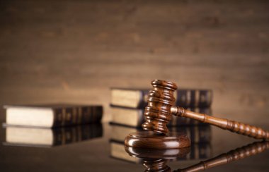 Hukuk teması. Yargıç tokmak ve kahverengi arkaplan üzerine hukuk kitapları koleksiyonu. 