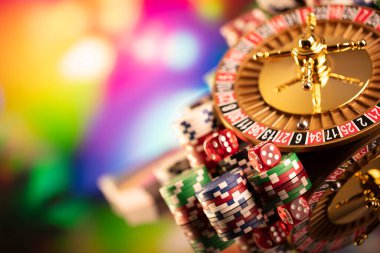 Kumarhane teması. Rulet çarkı, poker çipleri ve renkli arkaplanda zarlar.