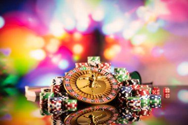 Kumarhane teması. Rulet çarkı, poker çipleri ve renkli arkaplanda zarlar.