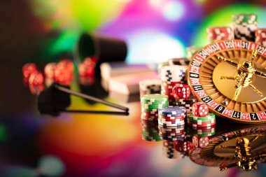 Kumarhane teması. Rulet çarkı, poker çipleri ve renkli arkaplanda zarlar.