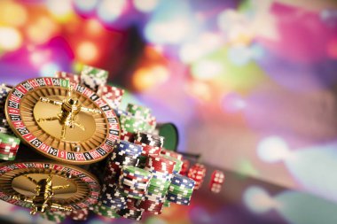 Kumarhane teması. Rulet çarkı, poker çipleri ve renkli arkaplanda zarlar.