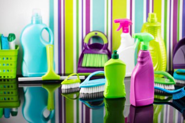 House and office cleaning theme. Colorful set of bottles with clining liquids and colorful cleaning kit on background in the form of colorful stripes. clipart
