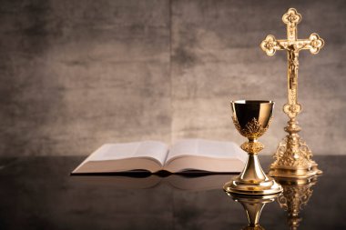 Katolik sembolleri kompozisyonu. Din kavramı. Haç, Monstrance, Kutsal İncil ve Altın Kadeh gri arka plan. 