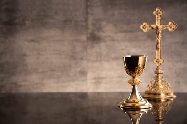 Katolik sembolleri kompozisyonu. Din kavramı. Haç, Monstrance, Kutsal İncil ve Altın Kadeh gri arka plan. 