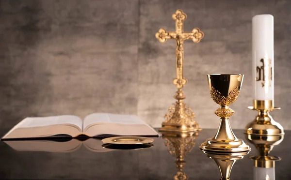 Catholic symbols composition. Religion concept. The Cross, monstrance,  Holy Bible and golden chalice gray background.