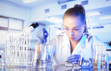 Laboratuvar konsepti. Deney sırasında genç bilim adamı modern laboratuvarda mikroskop kullanıyor..