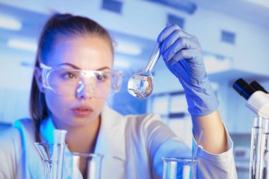 Laboratuvar konsepti. Deney sırasında genç bilim adamı modern laboratuvarda mikroskop kullanıyor..