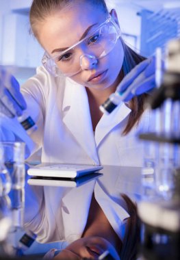 Laboratuvar konsepti. Deney sırasında genç bilim adamı modern laboratuvarda mikroskop kullanıyor..