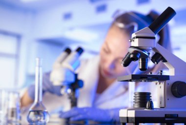 Laboratuvar konsepti. Deney sırasında genç bilim adamı modern laboratuvarda mikroskop kullanıyor..