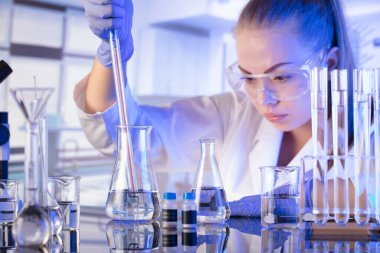 Laboratuvar konsepti. Deney sırasında genç bilim adamı modern laboratuvarda mikroskop kullanıyor..