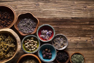 Doğal tıp geçmişi. Kâselerde çeşitli kuru otlar ve rustik ahşap masa üzerinde pirinç havan..