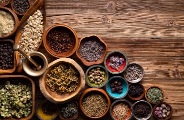 Doğal tıp geçmişi. Kâselerde çeşitli kuru otlar ve rustik ahşap masa üzerinde pirinç havan..