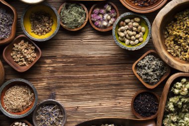 Doğal tıp geçmişi. Kâselerde çeşitli kuru otlar ve rustik ahşap masa üzerinde pirinç havan..