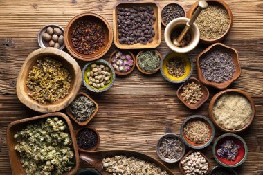 Doğal tıp geçmişi. Kâselerde çeşitli kuru otlar ve rustik ahşap masa üzerinde pirinç havan..