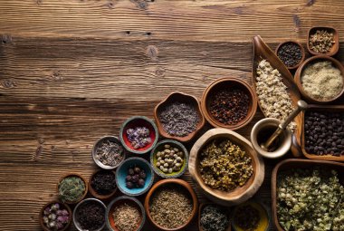 Doğal tıp geçmişi. Kâselerde çeşitli kuru otlar ve rustik ahşap masa üzerinde pirinç havan..