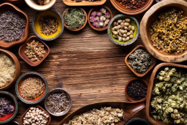 Doğal tıp geçmişi. Kâselerde çeşitli kuru otlar ve rustik ahşap masa üzerinde pirinç havan..