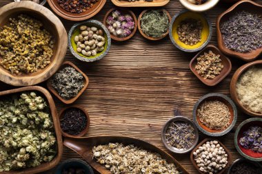 Doğal tıp geçmişi. Kâselerde çeşitli kuru otlar ve rustik ahşap masa üzerinde pirinç havan..