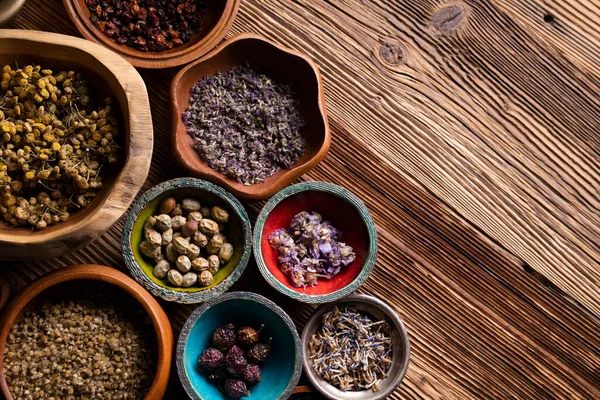 Doğal tıp geçmişi. Kâselerde çeşitli kuru otlar ve rustik ahşap masa üzerinde pirinç havan..