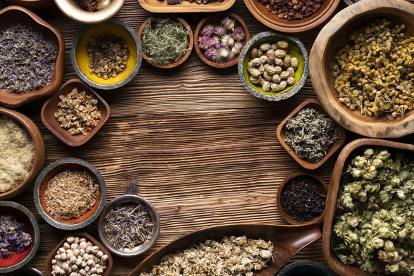 Doğal tıp geçmişi. Kâselerde çeşitli kuru otlar ve rustik ahşap masa üzerinde pirinç havan..
