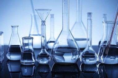 Laboratuvar araştırmaları. Mavi arka planda cam tüpler ve beherler.