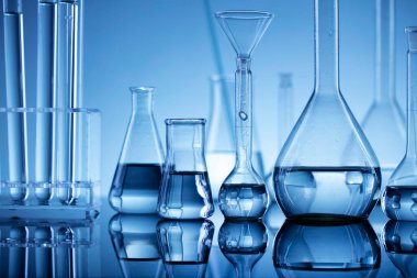 Laboratuvar araştırmaları. Mavi arka planda cam tüpler ve beherler.