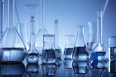 Laboratuvar araştırmaları. Mavi arka planda cam tüpler ve beherler.