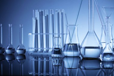 Laboratuvar araştırmaları. Mavi arka planda cam tüpler ve beherler.