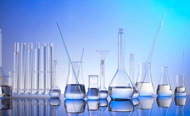 Laboratuvar araştırmaları. Mavi arka planda cam tüpler ve beherler.