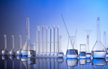 Laboratuvar araştırmaları. Mavi arka planda cam tüpler ve beherler.