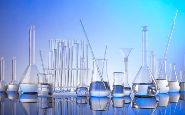 Laboratuvar araştırmaları. Mavi arka planda cam tüpler ve beherler.