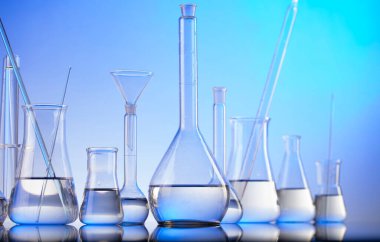 Laboratuvar araştırmaları. Mavi arka planda cam tüpler ve beherler.