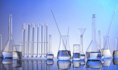 Laboratuvar araştırmaları. Mavi arka planda cam tüpler ve beherler.