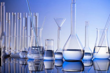 Laboratuvar araştırmaları. Mavi arka planda cam tüpler ve beherler.