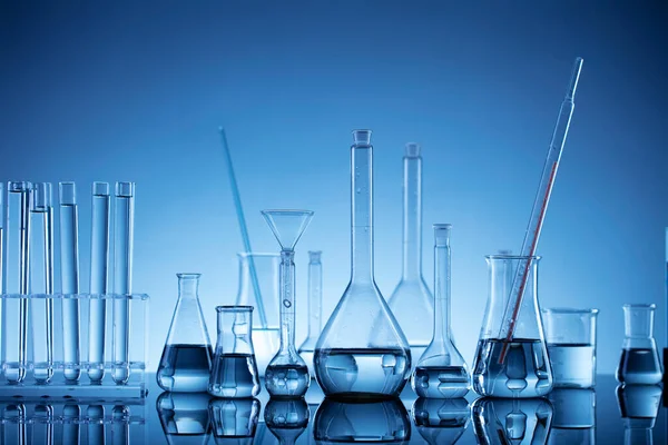Laboratuvar araştırmaları. Mavi arka planda cam tüpler ve beherler.