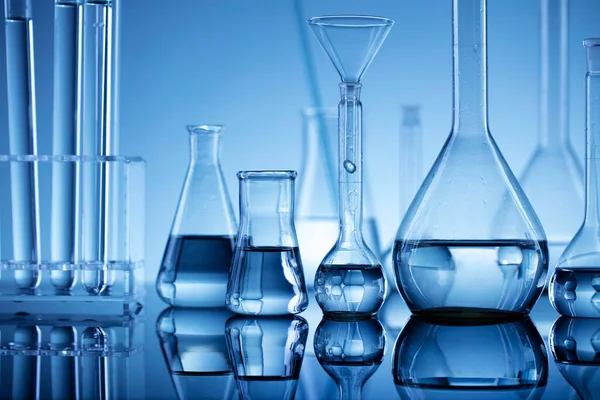 Laboratuvar araştırmaları. Mavi arka planda cam tüpler ve beherler.