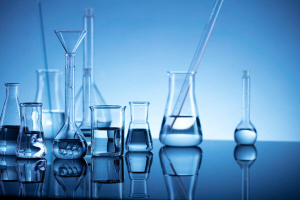 Laboratory investigations. Glass tubes and beakers on blue background.